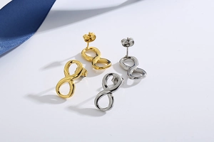 Detail of infinity symbol stud earrings in gold and silver finish on a blue ribbon