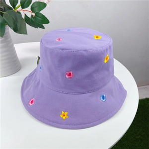 Top view of purple cotton sun hat with colorful flower embroidery on white table