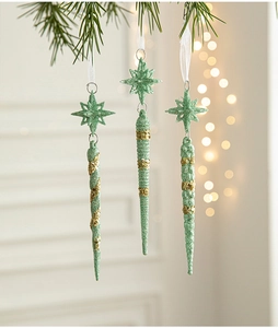 Close-up of mint green icicle ornaments with gold glitter on Christmas tree branches