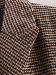 Close-up detail of the houndstooth pattern fabric on a stylish mid-length blazer lapel