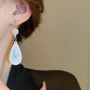 Detail view of water drop earrings with delicate light blue lily patterns on white resin