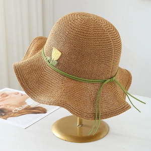 Close-up of hand-woven straw hat with delicate green ribbon and tulip flower embroidery