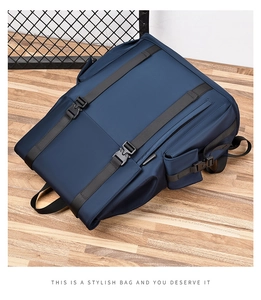 Top view of a navy blue nylon backpack with black straps and buckles on a wooden floor