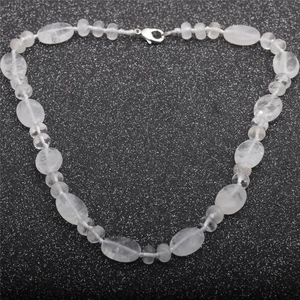 Macro detail of white translucent quartz beads with silver lobster clasp on a black background
