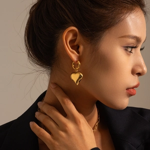 Close-up of elegant gold heart-shaped earrings and minimalist chain necklace on a model