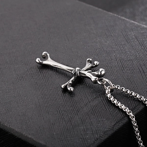 Detailed view of silver cross pendant made of bone shapes on a textured surface