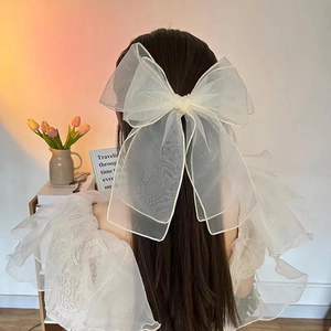 Elegant off-white organza oversized bow hair clip shown on model's hair in home setting