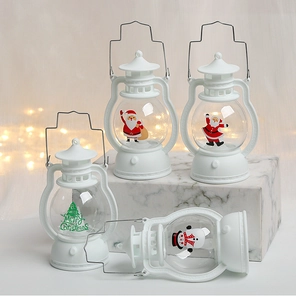 Detail view of white Christmas LED lanterns with Santa and snowman prints on marble surface