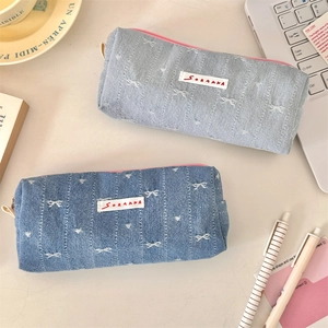Close-up of denim pencil case with diamond stitching, pink zipper, and woven label detail