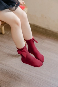 Detailed view of burgundy cotton girl socks featuring silk bow and ruffled trim