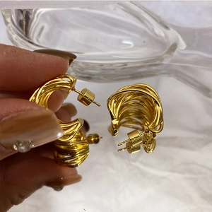 Macro shot of 925 silver needle gold plated C-shaped twisted layered metal earrings