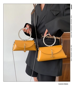Detail of bright yellow leather handbag with rhinestone ring handle and metal chain strap