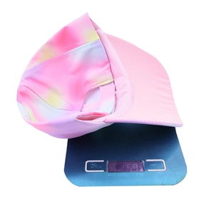 Lightweight pink tie-dye kids baseball cap on a blue digital scale showing portability