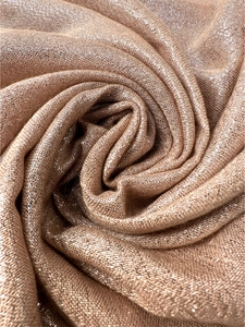 Macro shot of rose gold metallic sparkling knit fabric texture with tassel threads