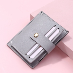 Detail of grey lychee faux leather card holder with snap buckle on pink geometric stand