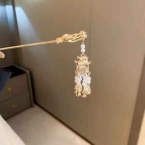 Détail d'un pic à cheveux doré vintage avec un pendentif pavillon et des perles