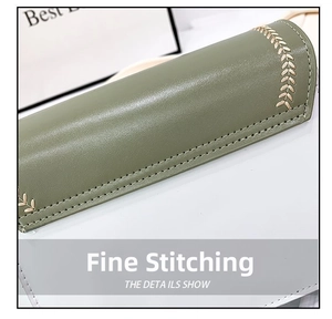 Close-up of fine stitching and gold leaf embroidery on dark green leather crossbody bag