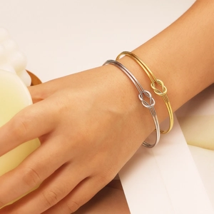 Detail of C-shaped knot bangles in gold and silver finish worn on a wrist