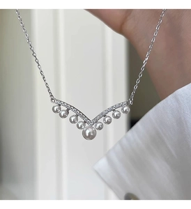 Detail of V-shaped silver necklace with gradient pearls and small sparkling zircons