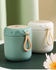 Close-up of portable insulated soup cups with wood grain lids and silicone carry handles