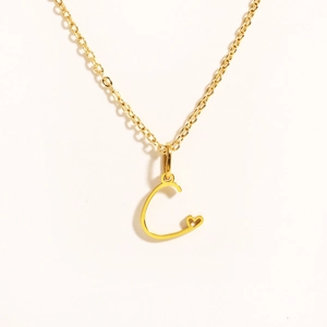 Detailed view of gold necklace featuring letter C pendant with small heart detail