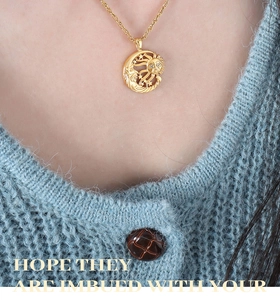 Detailed view of sun and moon pendant necklace worn over a light blue sweater