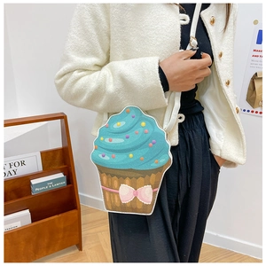 Cupcake-shaped crossbody bag with blue cream top and pink bow worn by a model