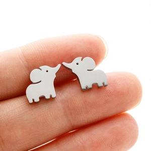 Macro shot of silver elephant stud earrings on fingertips showing smooth metallic finish