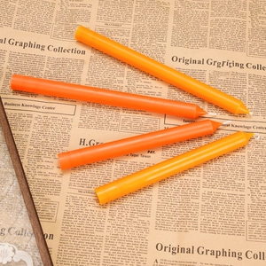 Taper candles in orange and yellow shades placed on a vintage newspaper background