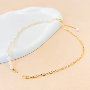 Detail of necklace with freshwater pearls and gold rectangular chain on a textured tray