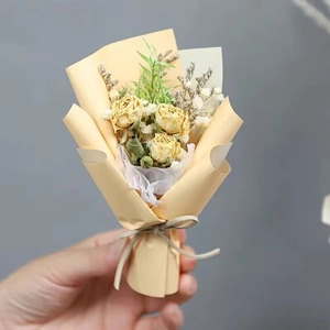 Close-up of mini yellow rose and baby's breath dried flower bouquet in paper wrapping