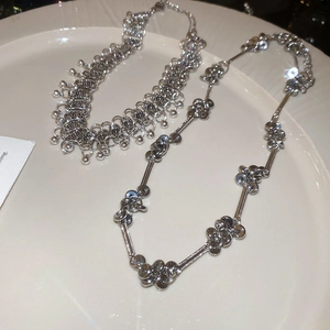 Close-up of metallic beaded tassel necklaces with shimmering starburst effects on white tray