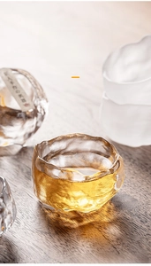Detailed view of frosted glass tea cup with hammered texture and smooth golden tea liquid