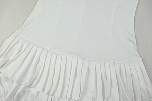 Detail of white pleated tiered dress fabric showing fine textured ruching and seams