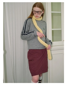 Close-up of yellow chunky knit scarf paired with grey sweatshirt and burgundy skirt
