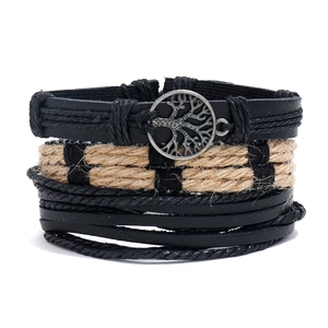Detail of layered black leather bracelets with woven hemp rope and tree of life metal charm