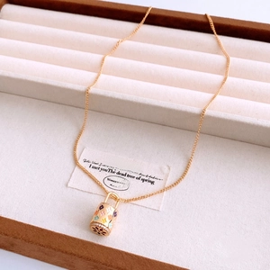 Détail d'un pendentif serrure en émail floral avec des zircons et une chaîne dorée