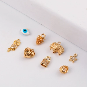 Selection of golden DIY jewelry charms with owl, evil eye, and heart designs