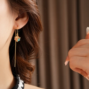 Close-up of elegant gold plated long earrings with blue and orange opal on model