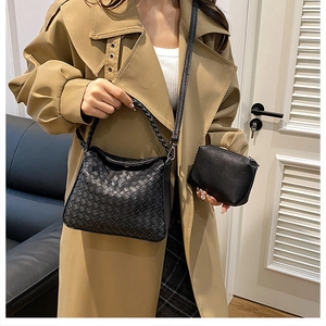 Detail view of black hand-woven tote bag and small pouch set styled with a trench coat