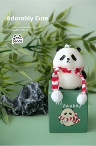 Close-up of a panda scented candle with a striped scarf and a green panda gift box