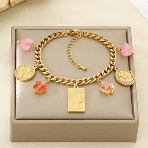 Detail of golden charm bracelet with pink heart beads and Elizabeth II coins in a jewelry box