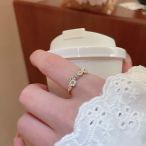 Close-up of golden floral open ring with white daisies and tiny colorful gemstones