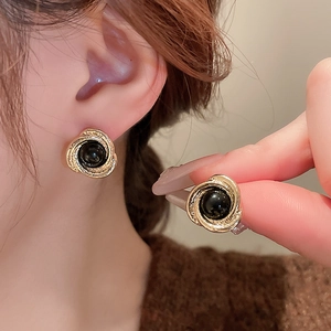 Detailed macro view of vintage tiger eye style round stud earrings with golden base