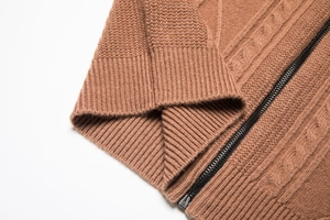 Detailed macro view of the brown knit cardigan's metal zipper and ribbed cuff texture