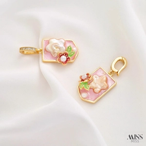 Macro detail of hand-painted floral charms with baroque pearls and gold enamel base