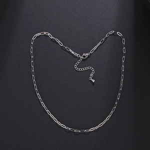 Minimalist silver stainless steel paperclip chain necklace on a dark textured background