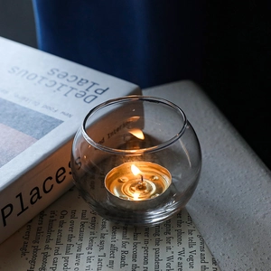 Nordic minimalist clear glass spherical candle holder with burning tealight on stone tabletop