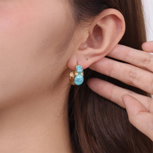 Close-up of C-shaped stainless steel earrings with dual blue natural stones on ear