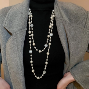Détail d'un collier de perles et d'opale française superposé sur un col roulé noir